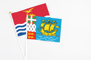 Saint Pierre And Miquelon and Kiribati stick flags on white background. High quality fabric, miniature national flag. Peaceful global concept.White floor for copy space.