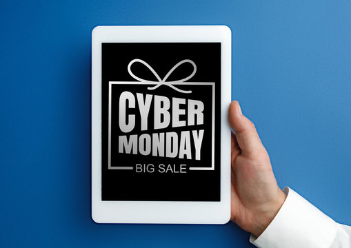 Male hand holding tablet with cyber monday words on blue background. Tech, modern, gadgets, business and advertising. Black friday, cyber monday, sales, finance, money online purchases concept.