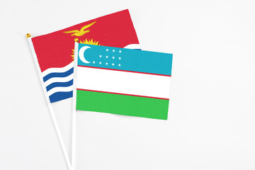 Uzbekistan and Kiribati stick flags on white background. High quality fabric, miniature national flag. Peaceful global concept.White floor for copy space.