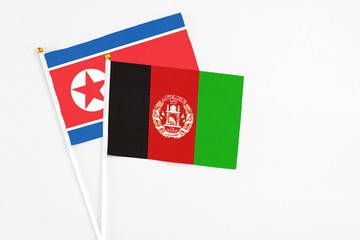 Afghanistan and North Korea stick flags on white background. High quality fabric, miniature national flag. Peaceful global concept.White floor for copy space.