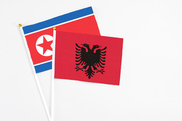 Albania and North Korea stick flags on white background. High quality fabric, miniature national flag. Peaceful global concept.White floor for copy space.