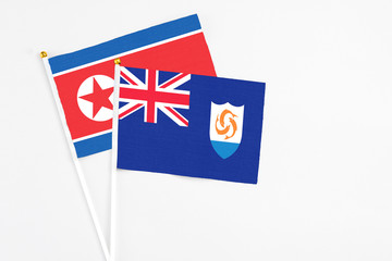 Fototapeta premium Anguilla and North Korea stick flags on white background. High quality fabric, miniature national flag. Peaceful global concept.White floor for copy space.