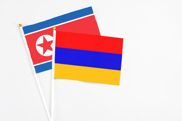 Armenia and North Korea stick flags on white background. High quality fabric, miniature national flag. Peaceful global concept.White floor for copy space.