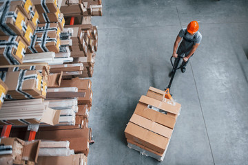 Top view of male worker in warehouse with pallet truck