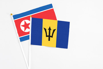 Barbados and North Korea stick flags on white background. High quality fabric, miniature national flag. Peaceful global concept.White floor for copy space.