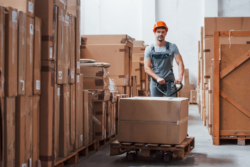 Young male worker in uniform is in the warehouse with pallet truck © standret