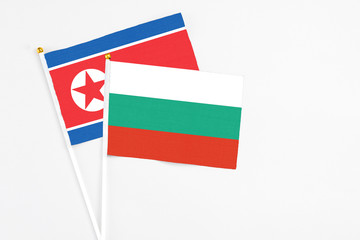 Bulgaria and North Korea stick flags on white background. High quality fabric, miniature national flag. Peaceful global concept.White floor for copy space.