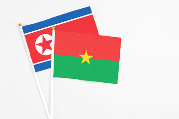 Burkina Faso and North Korea stick flags on white background. High quality fabric, miniature national flag. Peaceful global concept.White floor for copy space.