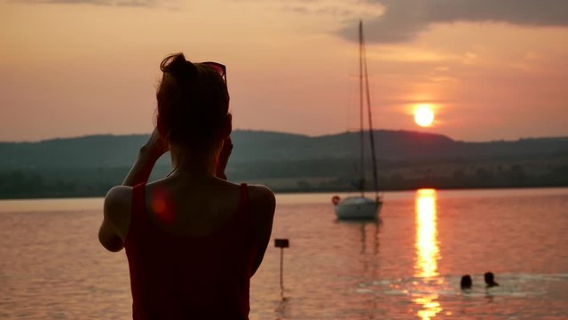 Nice woman silhouette takes photos in a beach at sunset Balaton, Hungary