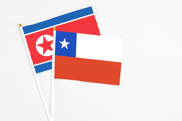Chile and North Korea stick flags on white background. High quality fabric, miniature national flag. Peaceful global concept.White floor for copy space.