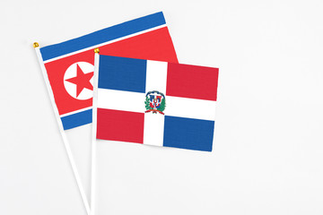 Dominican Republic and North Korea stick flags on white background. High quality fabric, miniature national flag. Peaceful global concept.White floor for copy space.