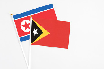 East Timor and North Korea stick flags on white background. High quality fabric, miniature national flag. Peaceful global concept.White floor for copy space.
