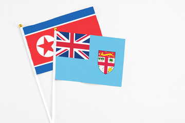 Fiji and North Korea stick flags on white background. High quality fabric, miniature national flag. Peaceful global concept.White floor for copy space.