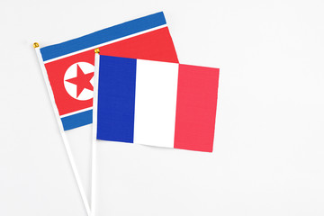 France and North Korea stick flags on white background. High quality fabric, miniature national flag. Peaceful global concept.White floor for copy space.