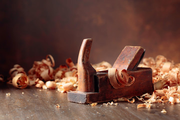 Old wooden jointer and shaving on wooden table. - obrazy, fototapety, plakaty