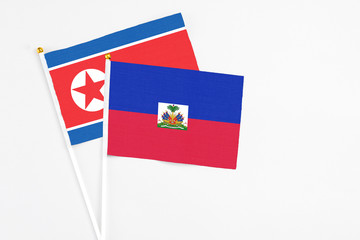 Haiti and North Korea stick flags on white background. High quality fabric, miniature national flag. Peaceful global concept.White floor for copy space.