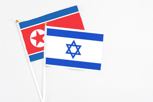 Israel and North Korea stick flags on white background. High quality fabric, miniature national flag. Peaceful global concept.White floor for copy space.