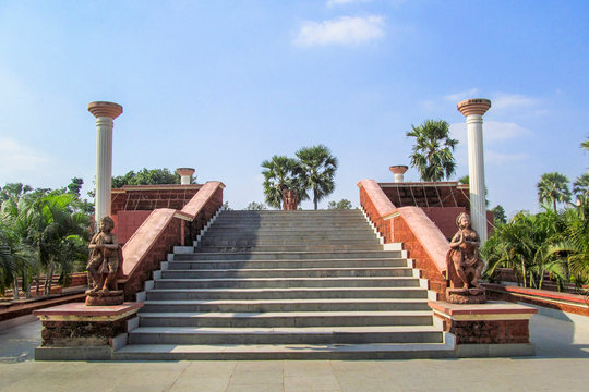 Picture of a beautiful park where two terracotta women statues are inviting everyone to go up the stairs up the pavilion