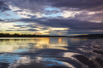 The tranquil waters of Lake Kununurra in the Kimberley region of Western Australia at sunset with tropical thunderstorms in the distance.