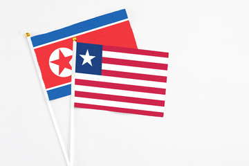 Liberia and North Korea stick flags on white background. High quality fabric, miniature national flag. Peaceful global concept.White floor for copy space.