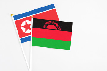 Malawi and North Korea stick flags on white background. High quality fabric, miniature national flag. Peaceful global concept.White floor for copy space.