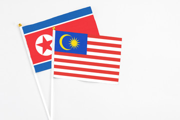 Malaysia and North Korea stick flags on white background. High quality fabric, miniature national flag. Peaceful global concept.White floor for copy space.