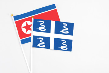 Martinique and North Korea stick flags on white background. High quality fabric, miniature national flag. Peaceful global concept.White floor for copy space.