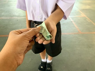 mother's hand is giving children money to spend in school