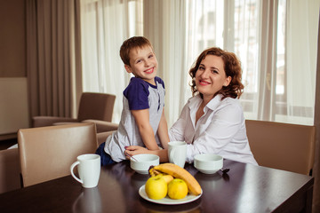 Happy family mother and son have breakfast in the kitchen.