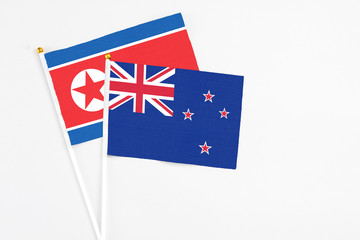 Fototapeta premium New Zealand and North Korea stick flags on white background. High quality fabric, miniature national flag. Peaceful global concept.White floor for copy space.