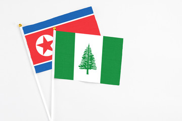 Norfolk Island and North Korea stick flags on white background. High quality fabric, miniature national flag. Peaceful global concept.White floor for copy space.