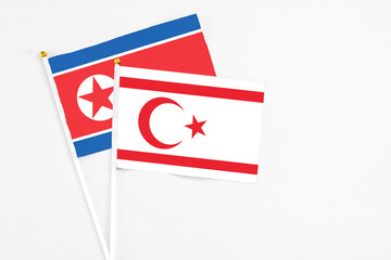 Northern Cyprus and North Korea stick flags on white background. High quality fabric, miniature national flag. Peaceful global concept.White floor for copy space.