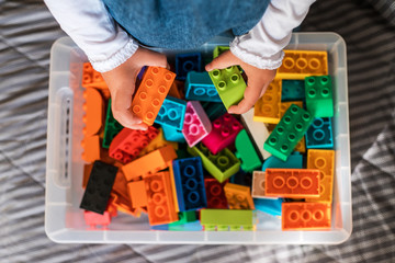 Little girl cleaning up the toy box at home. Child's space organization.