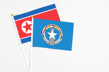Northern Mariana Islands and North Korea stick flags on white background. High quality fabric, miniature national flag. Peaceful global concept.White floor for copy space.