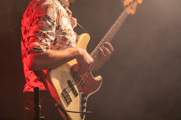 A close up view on electric guitar player viewed from the side as he wearing Shirt with flowers,...