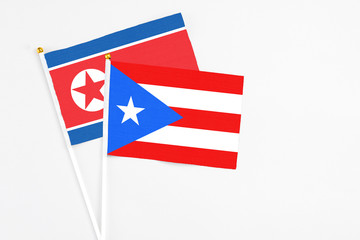Naklejka premium Puerto Rico and North Korea stick flags on white background. High quality fabric, miniature national flag. Peaceful global concept.White floor for copy space.