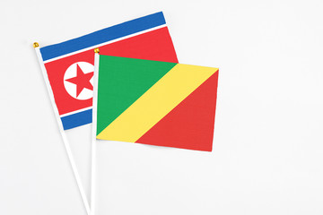 Republic Of The Congo and North Korea stick flags on white background. High quality fabric, miniature national flag. Peaceful global concept.White floor for copy space.