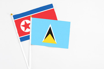 Saint Lucia and North Korea stick flags on white background. High quality fabric, miniature national flag. Peaceful global concept.White floor for copy space.