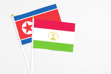 Tajikistan and North Korea stick flags on white background. High quality fabric, miniature national flag. Peaceful global concept.White floor for copy space.