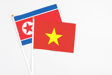 Vietnam and North Korea stick flags on white background. High quality fabric, miniature national flag. Peaceful global concept.White floor for copy space.
