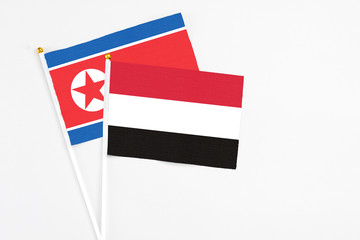 Yemen and North Korea stick flags on white background. High quality fabric, miniature national flag. Peaceful global concept.White floor for copy space.