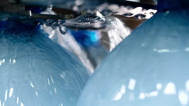 Industrial production of artesian clean water from natural wells on factory. Bottling fresh water in plastic bottles on automatic conveyor line on plant, closeup view. Manufacturing of drinking water.