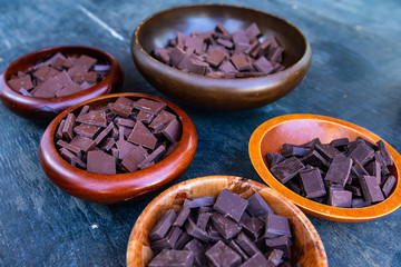 close up on dark chocolate chunks pieces in brown wooden bowls on the table, food during a spiritual gathering