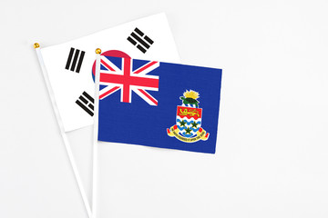 Fototapeta premium Cayman Islands and South Korea stick flags on white background. High quality fabric, miniature national flag. Peaceful global concept.White floor for copy space.