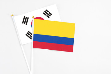 Colombia and South Korea stick flags on white background. High quality fabric, miniature national flag. Peaceful global concept.White floor for copy space.