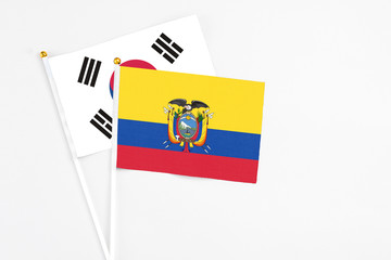 Ecuador and South Korea stick flags on white background. High quality fabric, miniature national flag. Peaceful global concept.White floor for copy space.