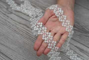 hand sewing beads pearls to the white lace silk fabric, making a wedding dress, decorating with embroidery