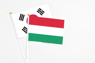 Hungary and South Korea stick flags on white background. High quality fabric, miniature national flag. Peaceful global concept.White floor for copy space.
