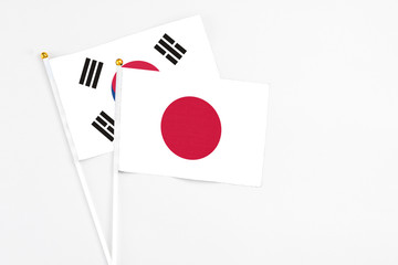 Japan and South Korea stick flags on white background. High quality fabric, miniature national flag. Peaceful global concept.White floor for copy space.