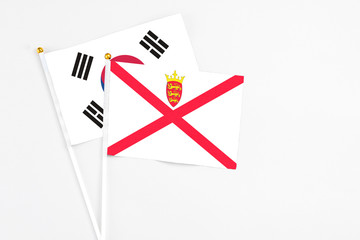 Jersey and South Korea stick flags on white background. High quality fabric, miniature national flag. Peaceful global concept.White floor for copy space.